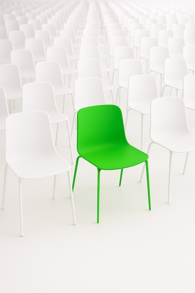 a green chair among many white chairs receding into the distance-1