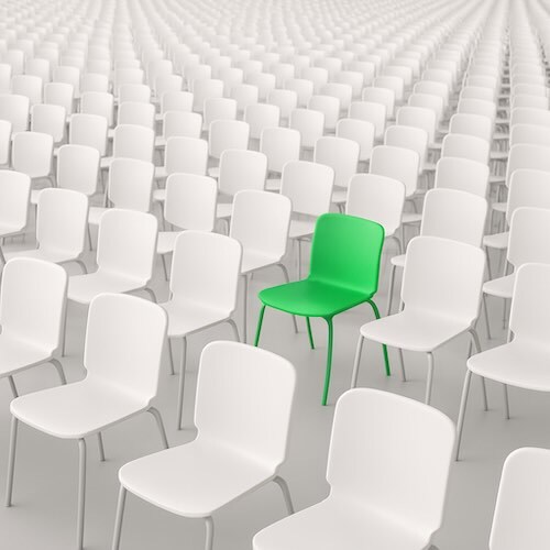 a single green chair among hundreds of white chairs